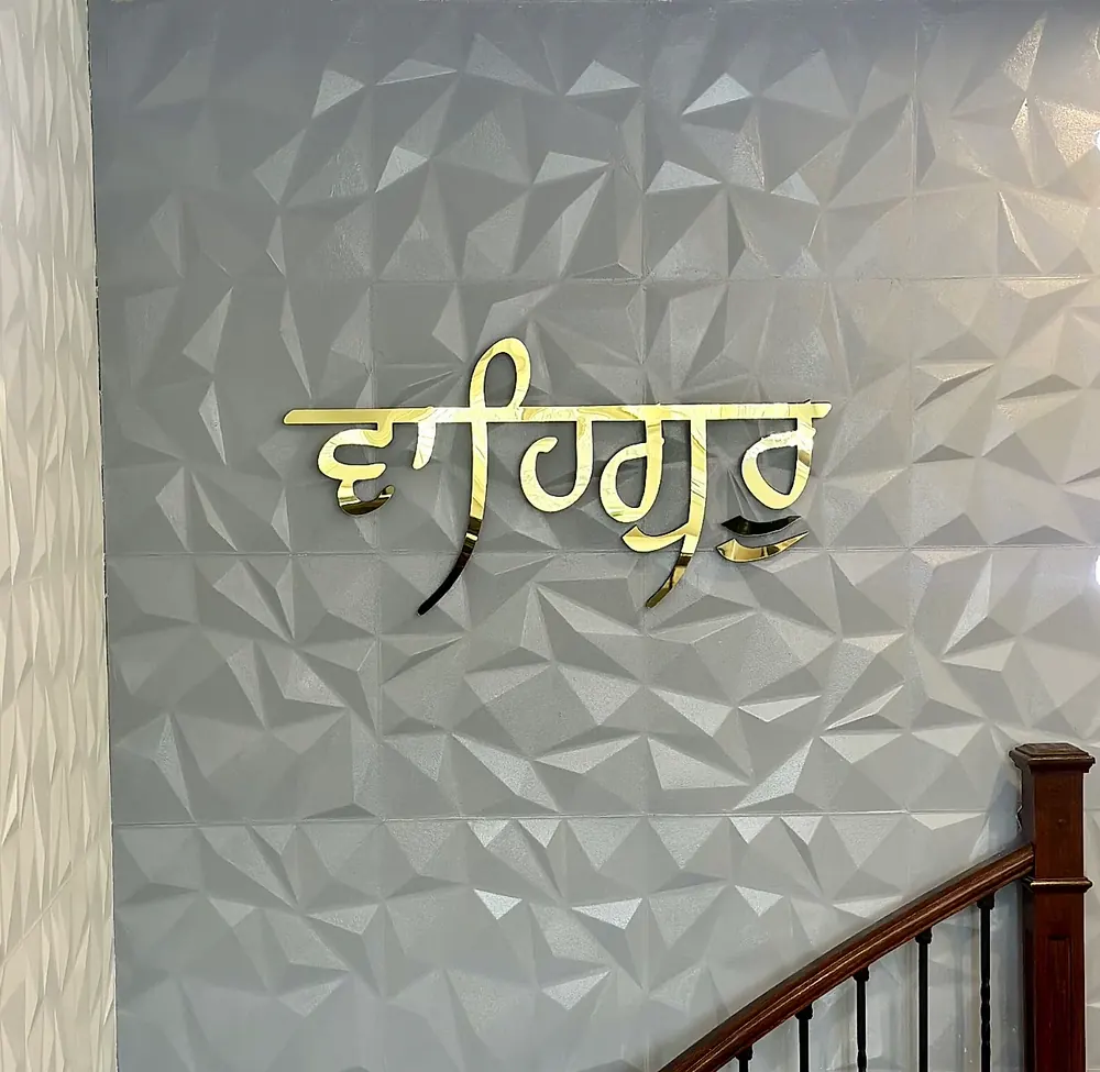 Gurmukhi lettering in gold on a textured interior feature wall