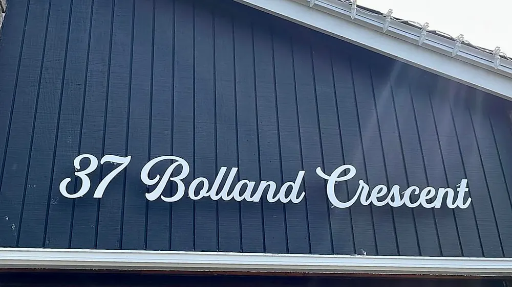 37 Bolland Crescent in white script on dark standing-seam siding