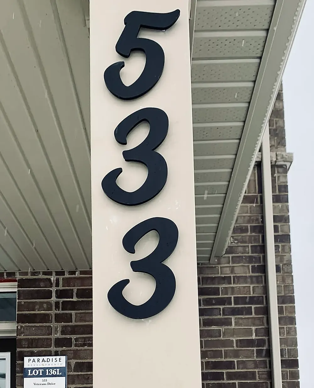 House numbers 5 3 3 stacked in matte black beside a front door