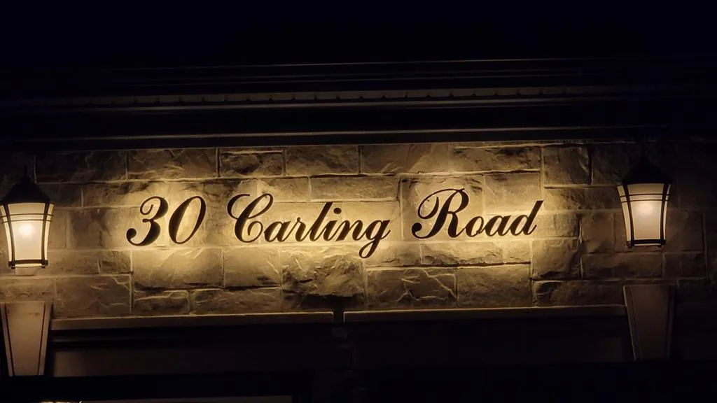 30 Carling Road in gold script, backlit against a dark house at night